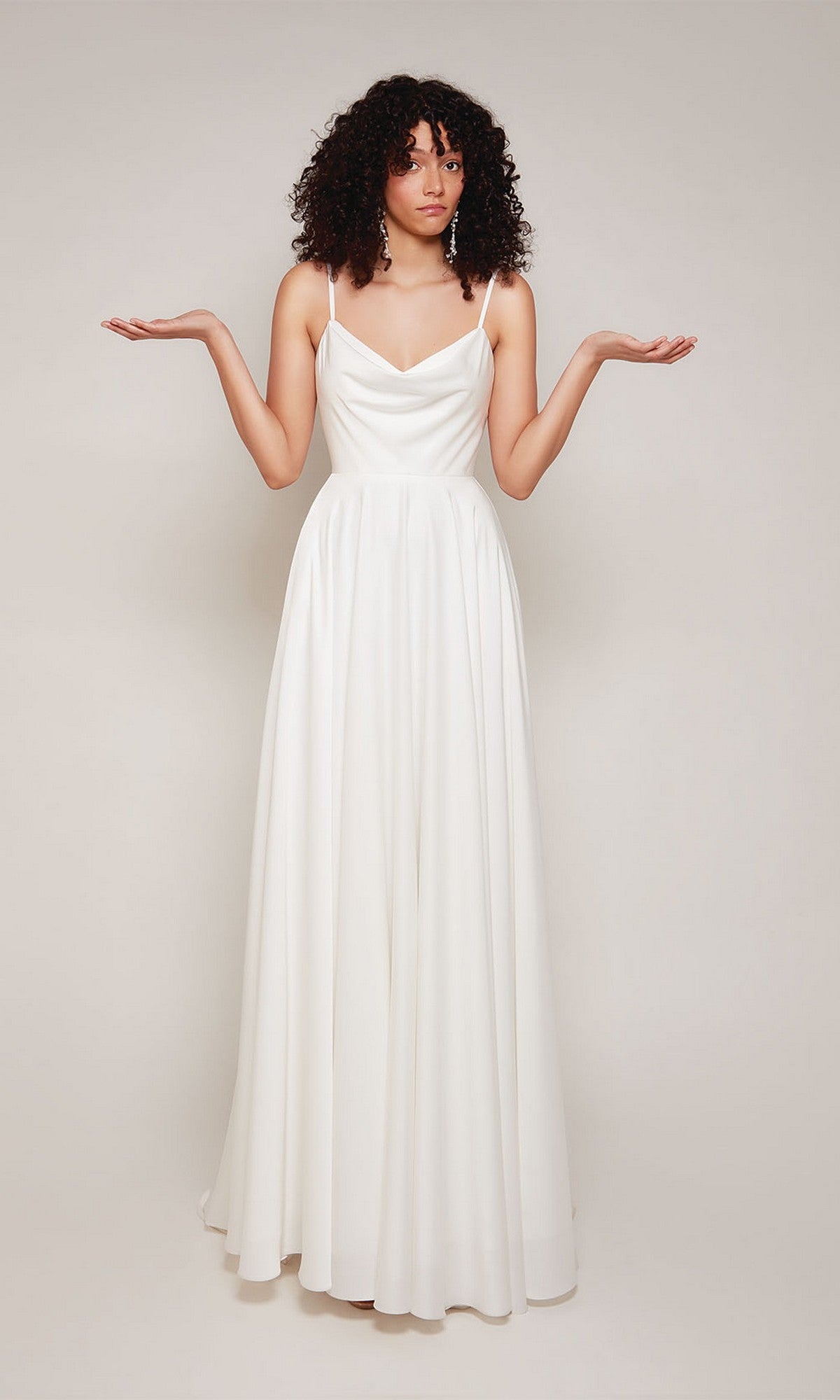A person with curly hair models the Alyce 7100 long formal dress, standing with arms raised and palms up against a plain background.